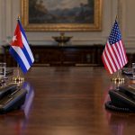 Banderas de Cuba y Estados Unidos en una mesa diplomática con teléfonos